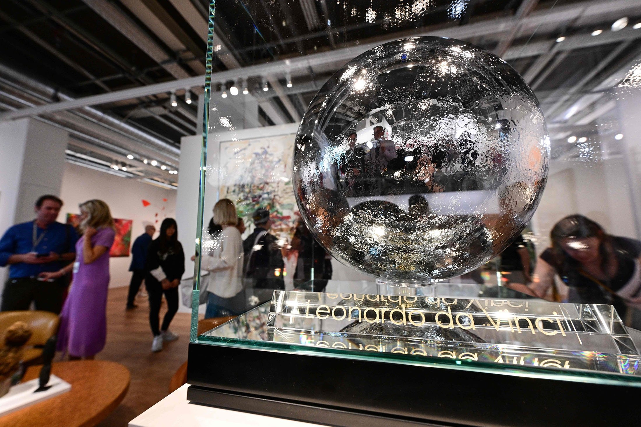 Visitors pass by a Jeff Koons artwork "moonfaces, Leonardo da Vinci" during a preview day of Art Basel, the world's premier modern and contemporary art fair in Basel, Switzerland, June 14, 2022. (AFP Photo)