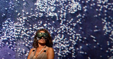 A visitor looks at a Wu Tsang virtual artwork &quot;A mighty mass emerges&quot; during a preview day of Art Basel, the world&#039;s premier modern and contemporary art fair in Basel, Switzerland, June 14, 2022. (AFP Photo)