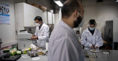 Food engineer Roberto Lemus (L) and food engineering students Marcelo Bertran (C) and Alonso Vasquez manipulate food as they work in a University of Chile lab, in Santiago, Chile, June 17, 2022. (AFP Photo)