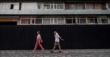 People walk past a residential area under lockdown due to COVID-19 restrictions in Beijing, China, June 15, 2022. (AFP Photo)