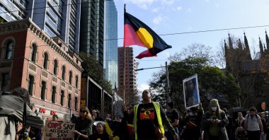 Protesters hold placards and the Aboriginal flag as they march during a protest against Indigenous deaths in custody in Sydney, Australia, June 18, 2022. (EPA Photo)