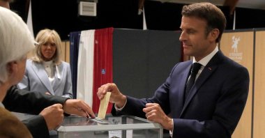 France's President Emmanuel Macron (R) casts his ballot next to his wife Brigitte Macron during the second stage of French parliamentary elections at a polling station in Le Touquet, northern France, June 19, 2022. (AFP Photo)