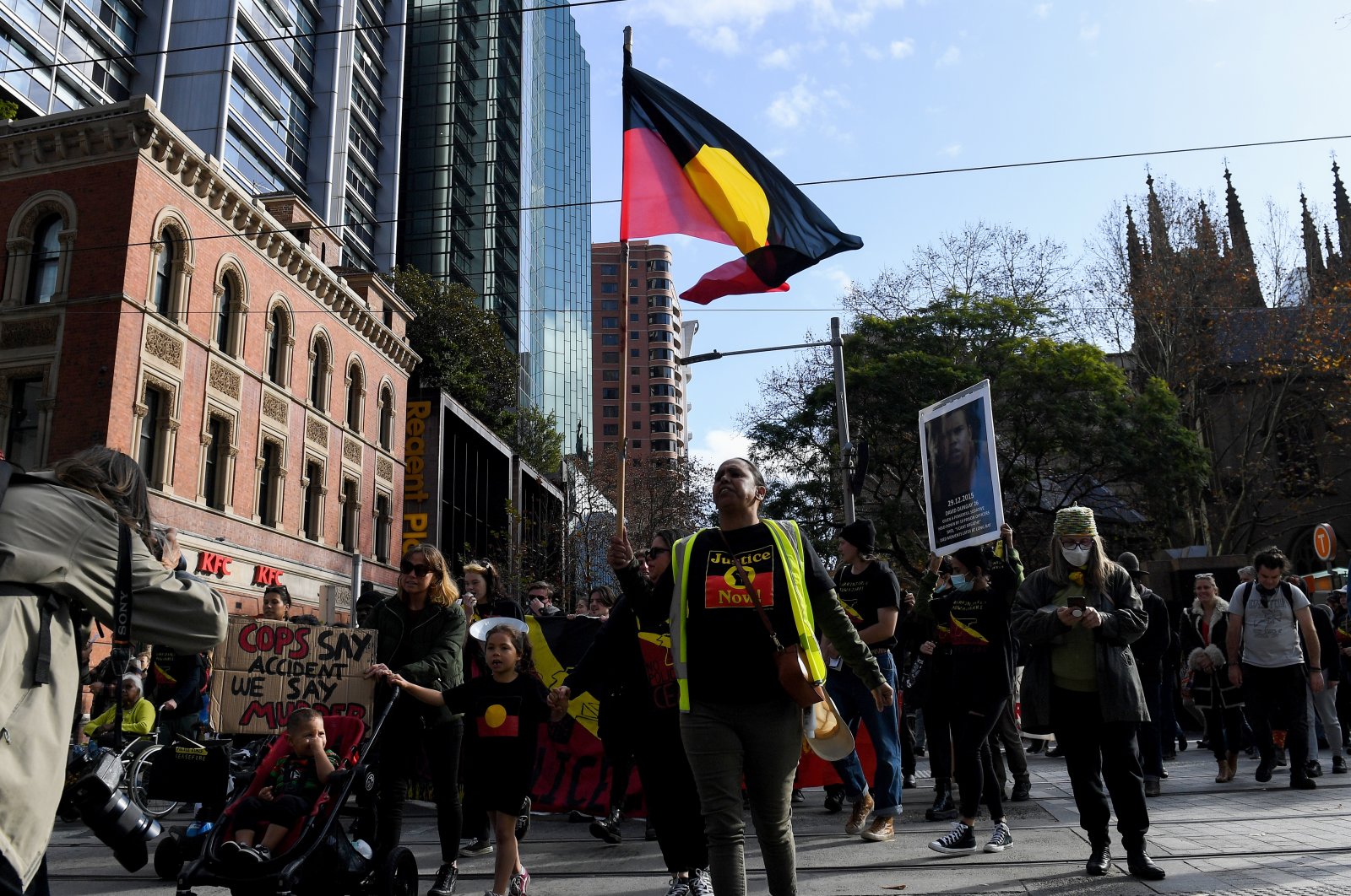 Protesters hold placards and the Aboriginal flag as they march during a protest against Indigenous deaths in custody in Sydney, Australia, June 18, 2022. (EPA Photo)