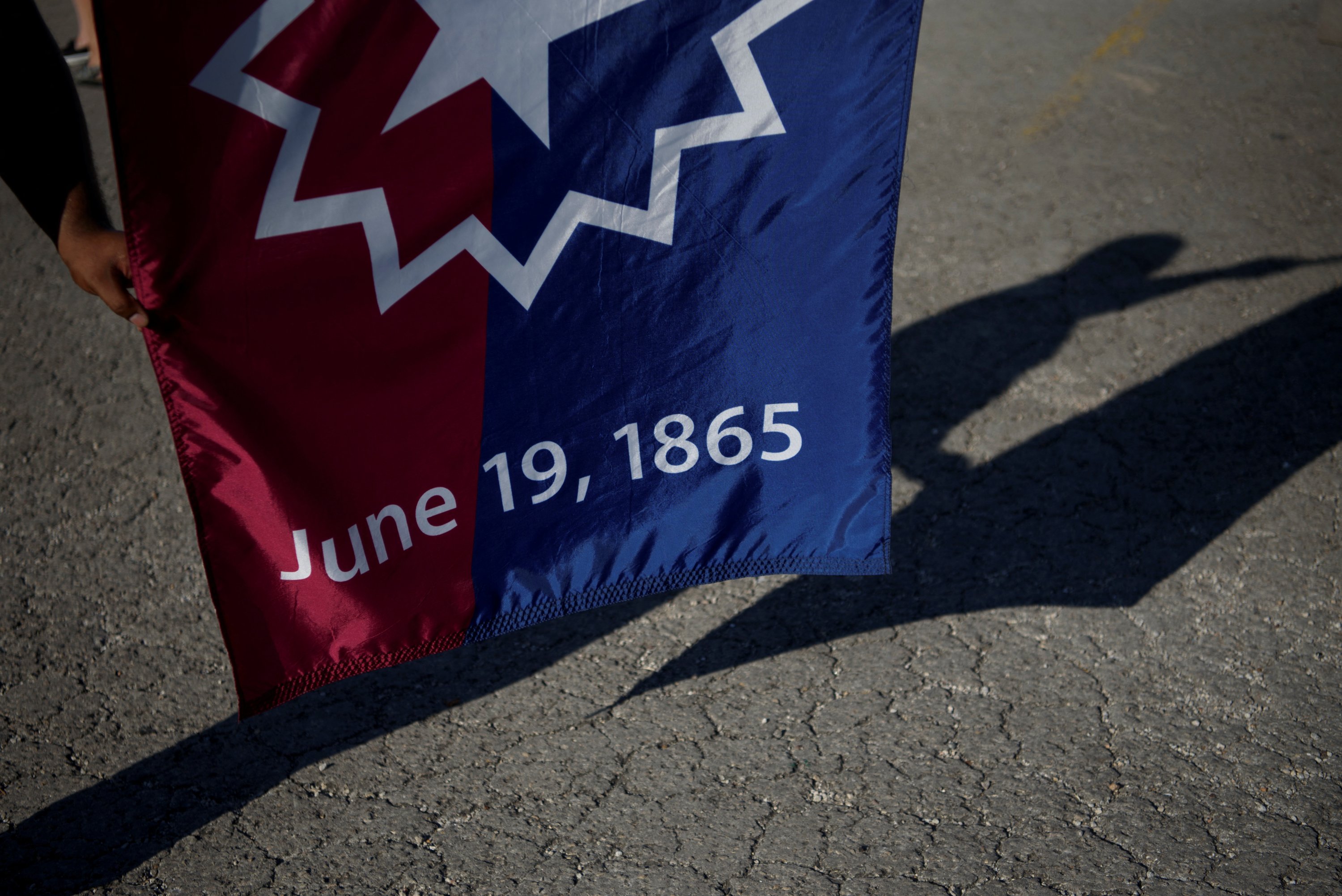 Seorang pria memegang bendera Juneteenth ketika orang-orang berkumpul untuk merayakan Juneteenth, memperingati berakhirnya perbudakan di Texas, dua tahun setelah Proklamasi Emansipasi 1863 membebaskan budak di tempat lain di Amerika Serikat, di Galveston, Texas, AS, 19 Juni 2022. (Reuters Foto)