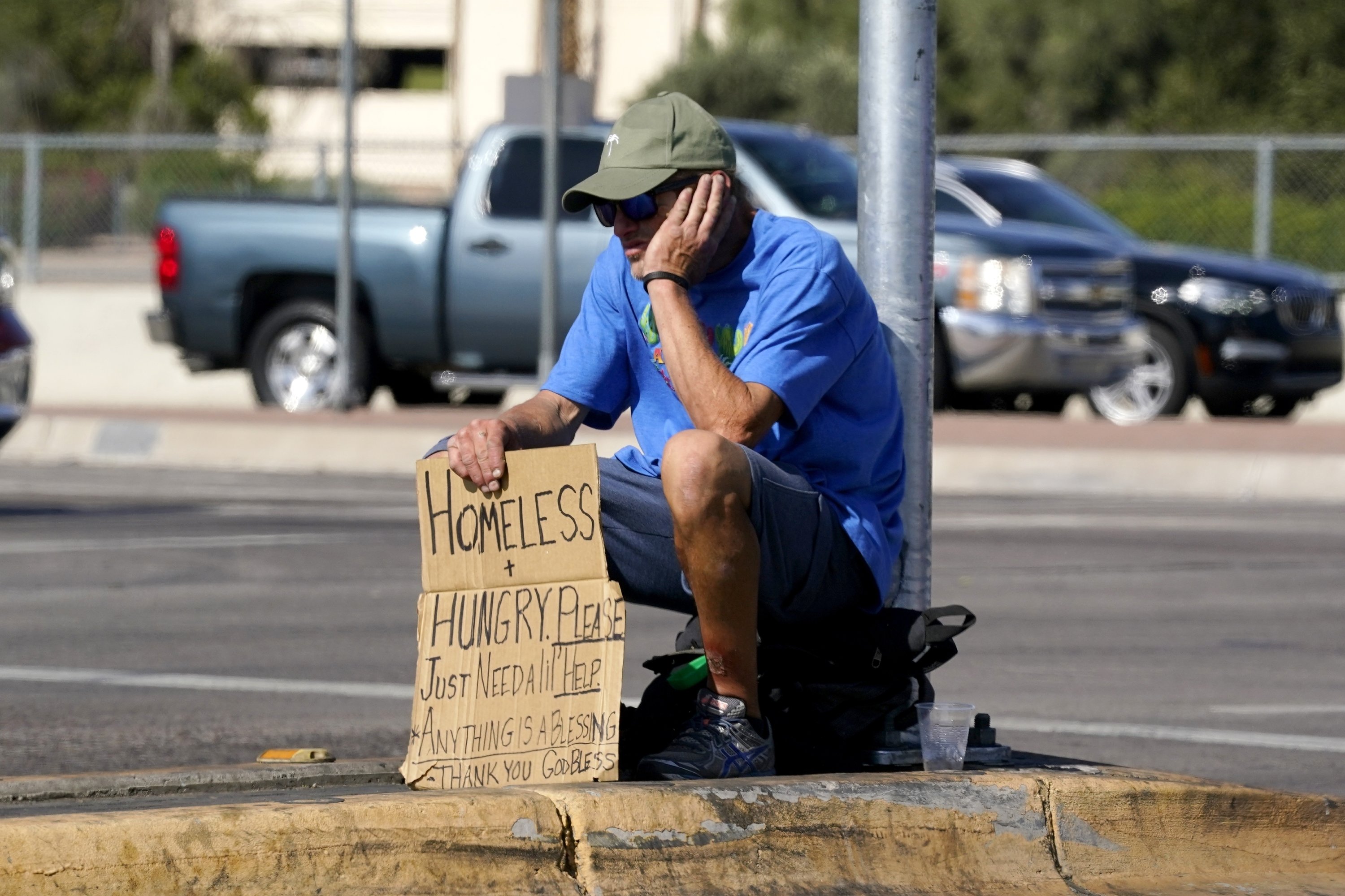 Seorang tunawisma duduk di median di persimpangan di Phoenix, Arizona, AS, 27 April 2022. (AP Photo)