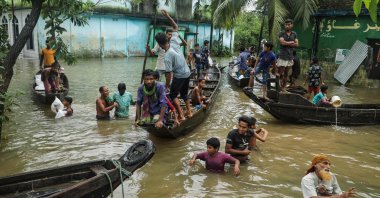People gather to collect food aid in a flooded residential area following heavy monsoon rainfalls in Companiganj, Bangladesh, June 20, 2022. (AFP Photo)