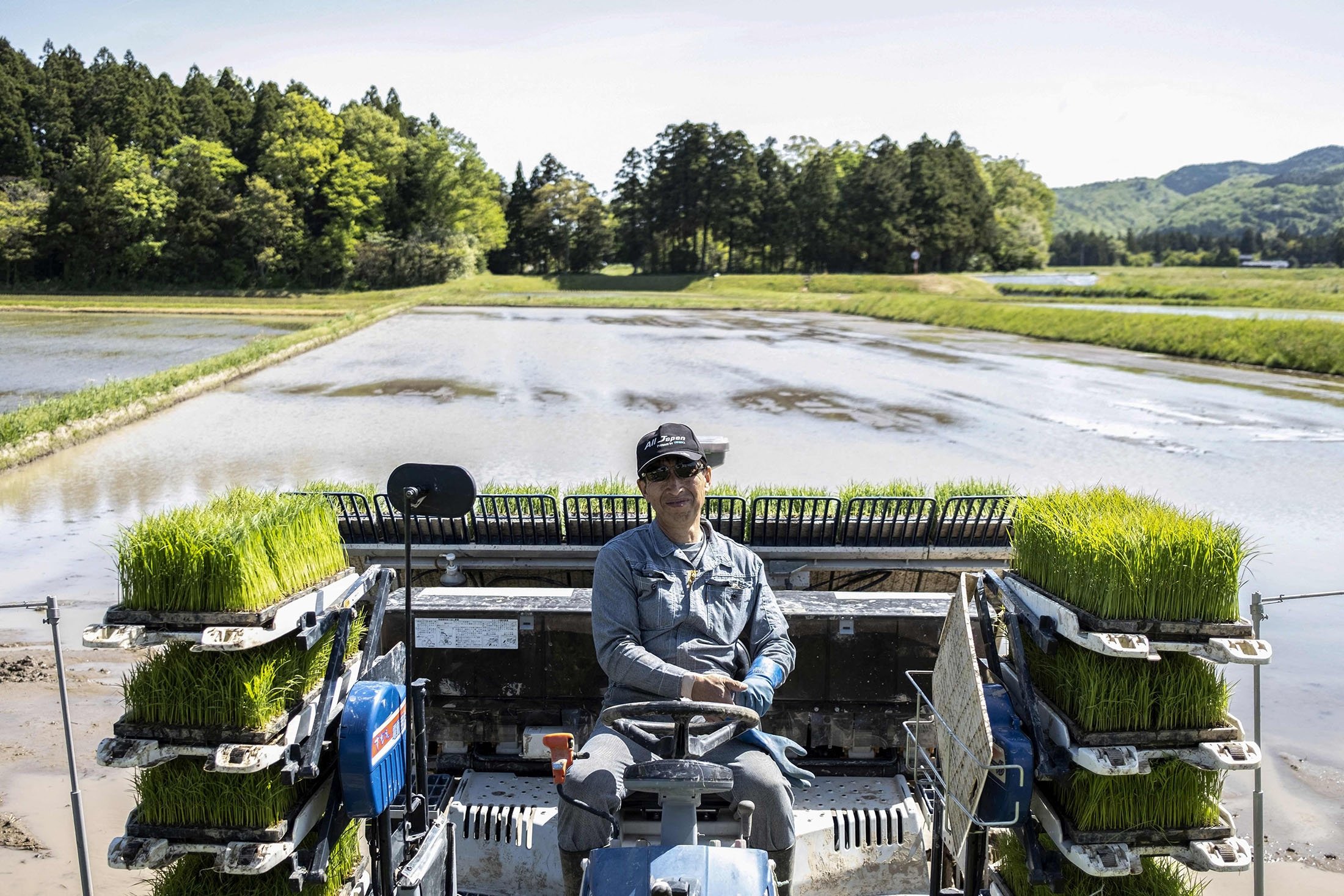 Farmer Shinichiro Saito poses on a rice planter in a paddy field where wild toki birds primarily feed, on Sado island, Niigata prefecture, Japan, May 8, 2022. (AFP Photo)