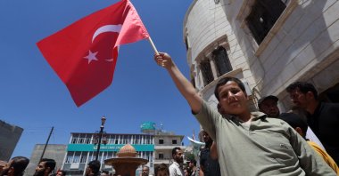 A young Syrian raises a Turkish flag as he participates in a rally in the border town of Azaz in the opposition-held north of the Aleppo province, northern Syria, June 5, 2022. (AFP)