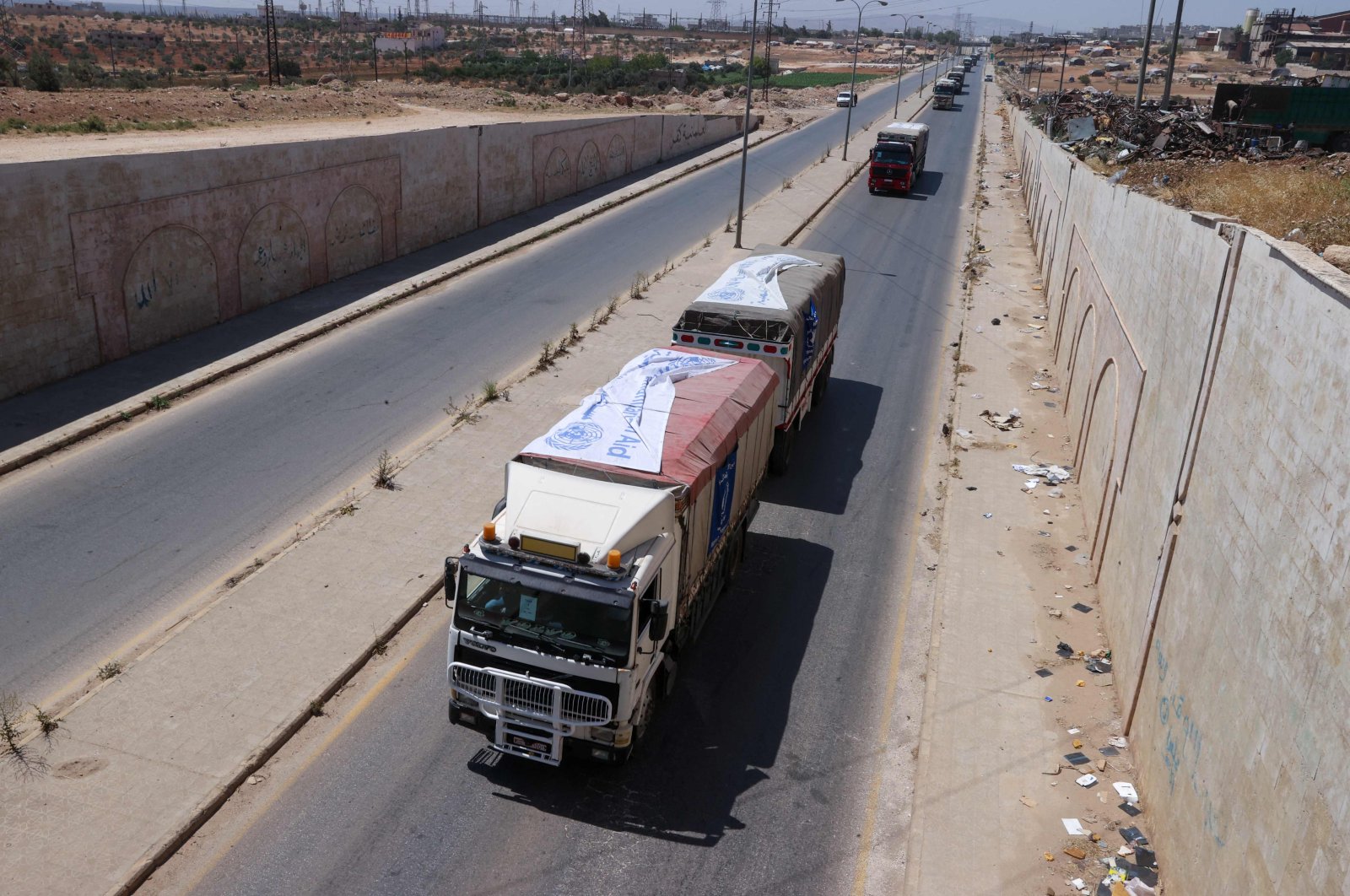 Trucks carrying aid packages from the World Food Program (WFP) drive through the town of Saraqib in the northwestern Idlib province on June 12, 2022. (Photo by OMAR HAJ KADOUR / AFP)