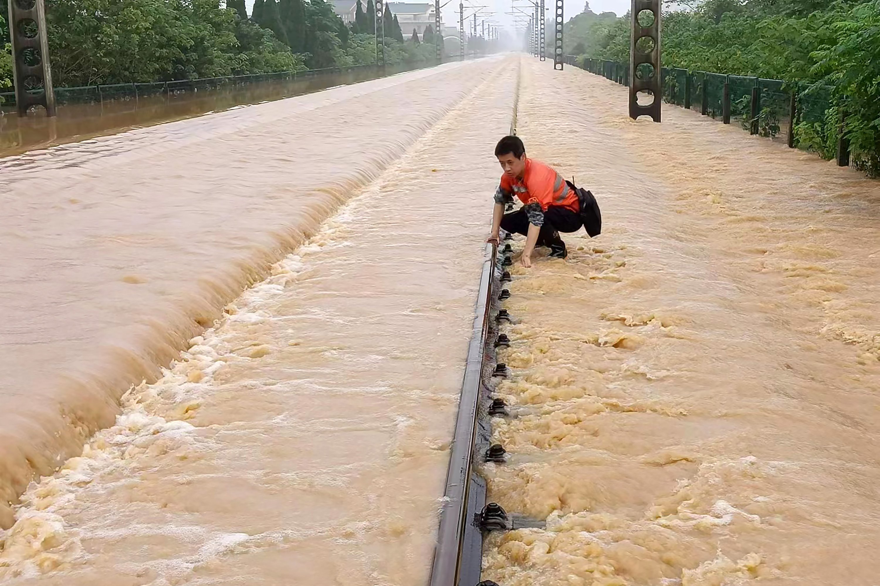 Seorang pekerja memeriksa bagian rel kereta api yang terendam banjir di Shangrao, provinsi Jiangxi, China, 21 Juni 2022. (AP Photo)