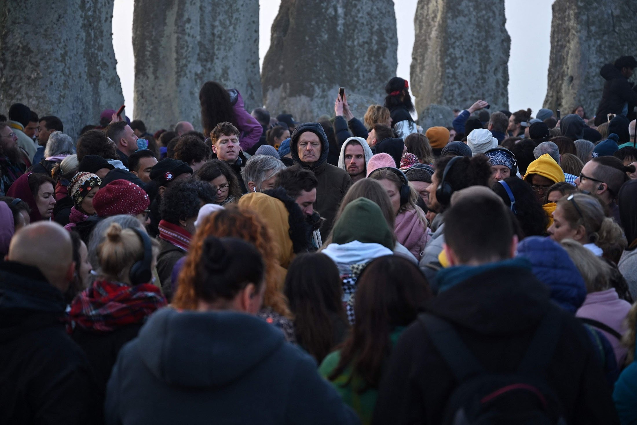 Orang-orang yang bersuka ria berinteraksi dengan monumen batu saat mereka merayakan Titik Balik Matahari Musim Panas saat matahari terbit di Stonehenge, dekat Amesbury, di Wiltshire, Inggris, 21 Juni 2022. (AFP Photo)