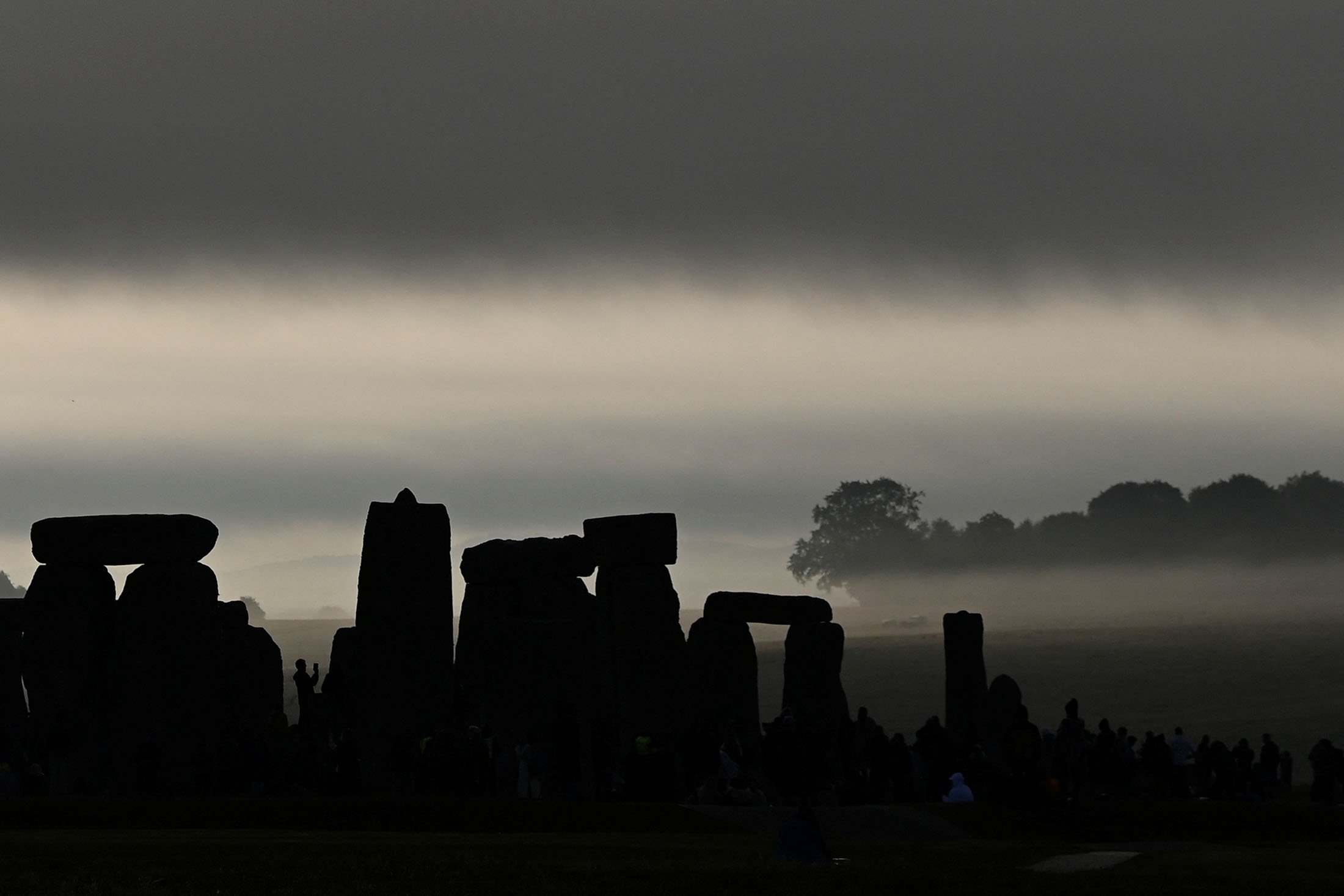 Orang-orang yang bersuka ria merayakan titik balik matahari musim panas di Stonehenge, dekat Amesbury, di Wiltshire, Inggris, 21 Juni 2022. (Foto Reuters)