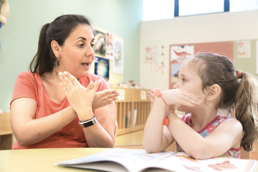 A sign language teacher in a tutoring class with a deaf child using American Sign Language. (Shutterstock Photo)