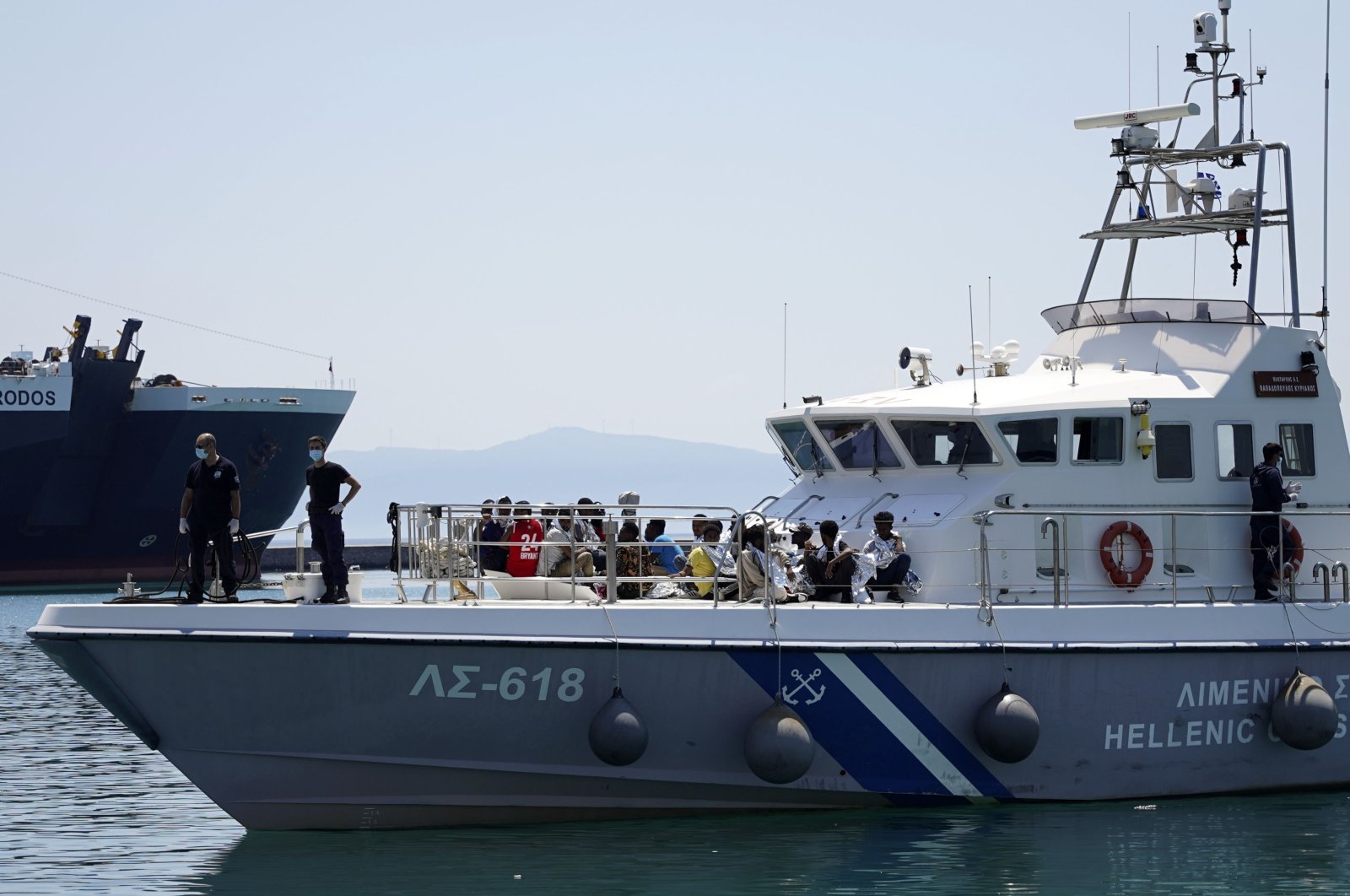 Migrants sit on the deck of a coast guard vessel upon their arrival at Mytilene port, on the northeastern Aegean Sea island of Lesbos, Greece, June 22, 2022. (AP)