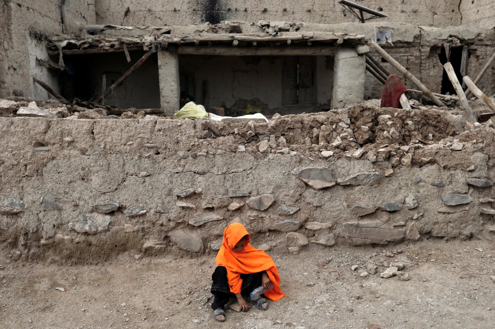 An Afghan girl sits in front of a house that was damaged by an earthquake in Gayan, Afghanistan, June 23, 2022. (Reuters Photo)