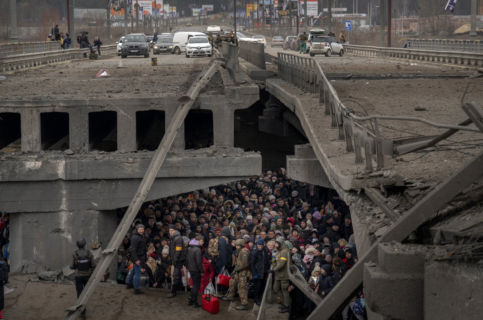 Ukrainians crowd under a destroyed bridge as they try to flee by crossing the Irpin River on the outskirts of Kyiv, Ukraine, March 5, 2022. (AP Photo)