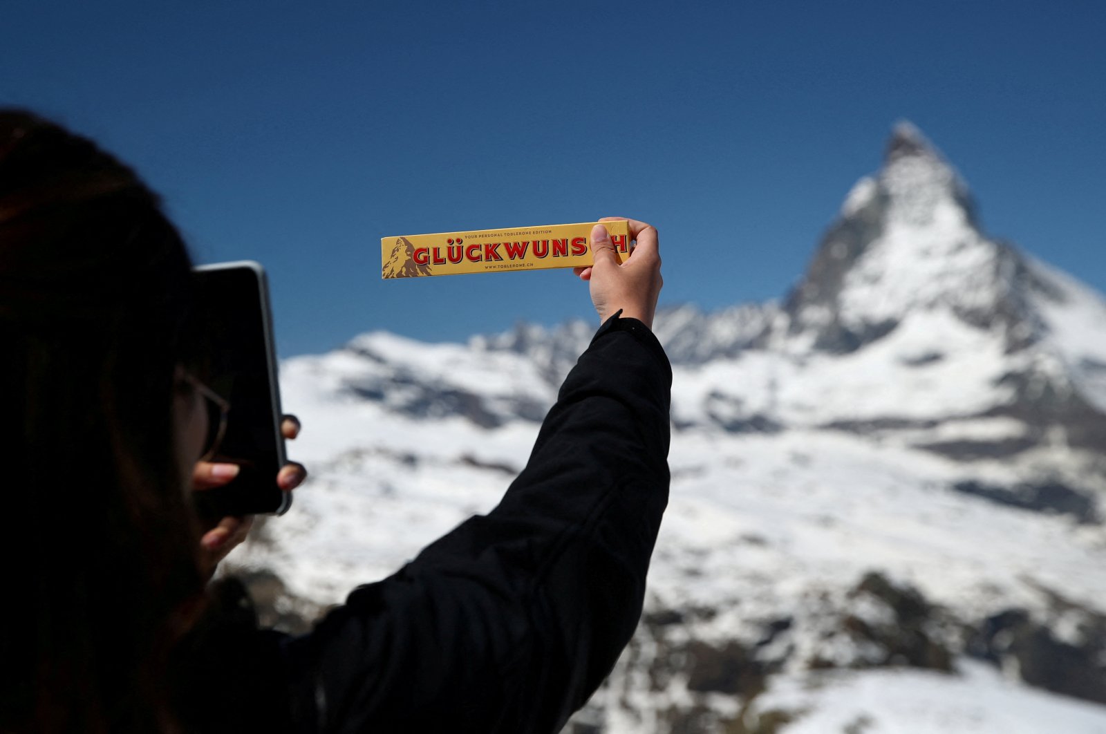 A tourist takes a picture of a Toblerone in front of the Matterhorn mountain at the Gornergrat in Zermatt, Switzerland June 2, 2019. (Reuters Photo)
