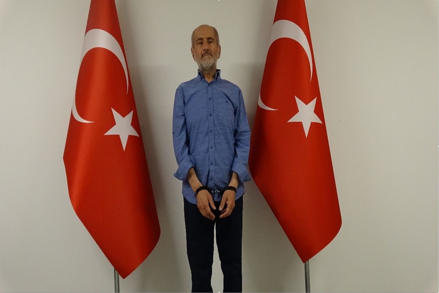 Greek National Intelligence Organization (EYP) spy Mohammed Amar Ampara, seen with handcuffs in front of two Turkish flags, after being caught by the National Intelligence Organization (MIT), Ankara, Turkey, June 25, 2022. (DHA Photo)