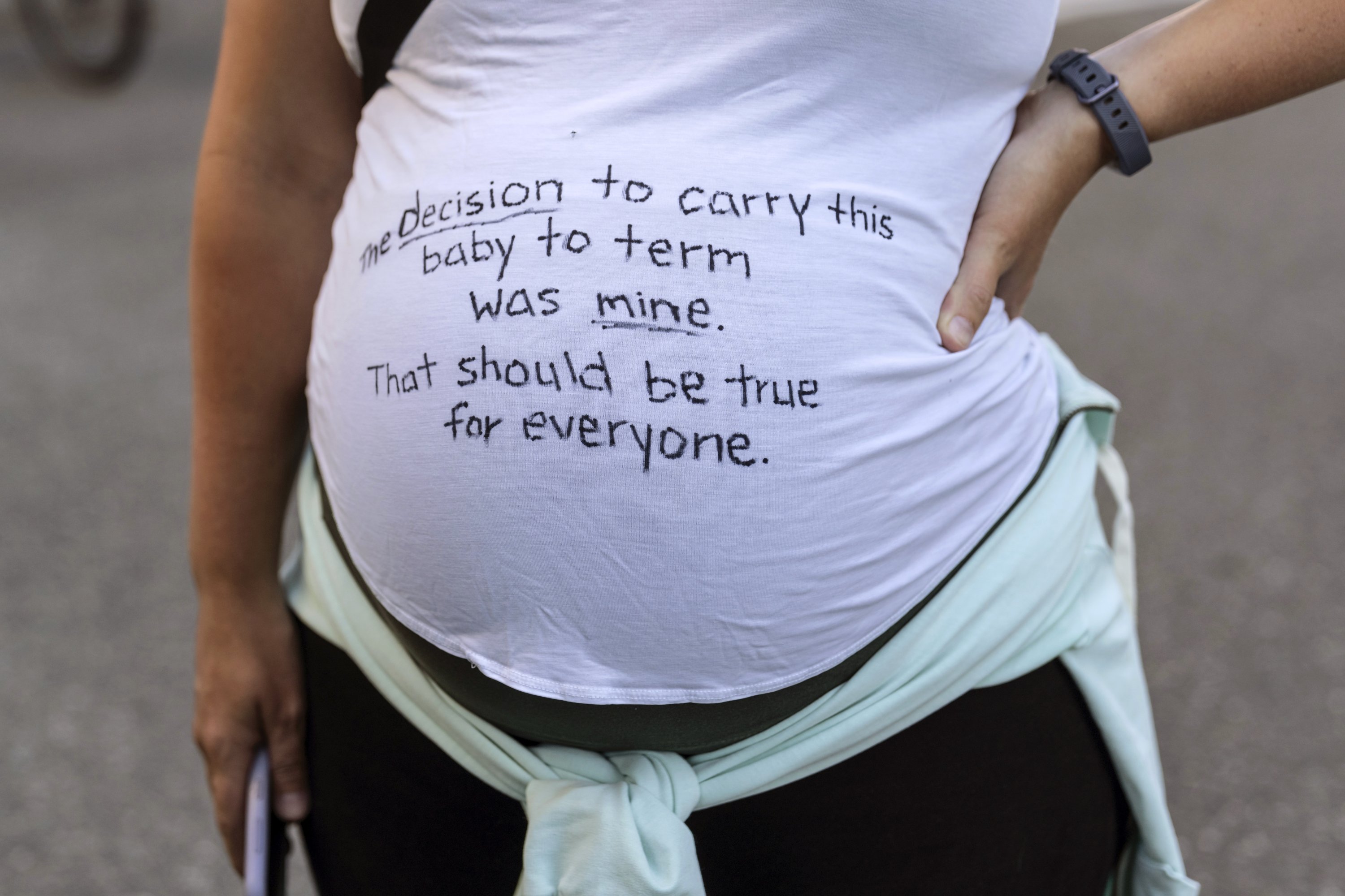 Seorang pengunjuk rasa hamil digambarkan dengan pesan di bajunya untuk mendukung hak aborsi selama pawai, Seattle, Washington, AS, 24 Juni 2022. (AP Photo)