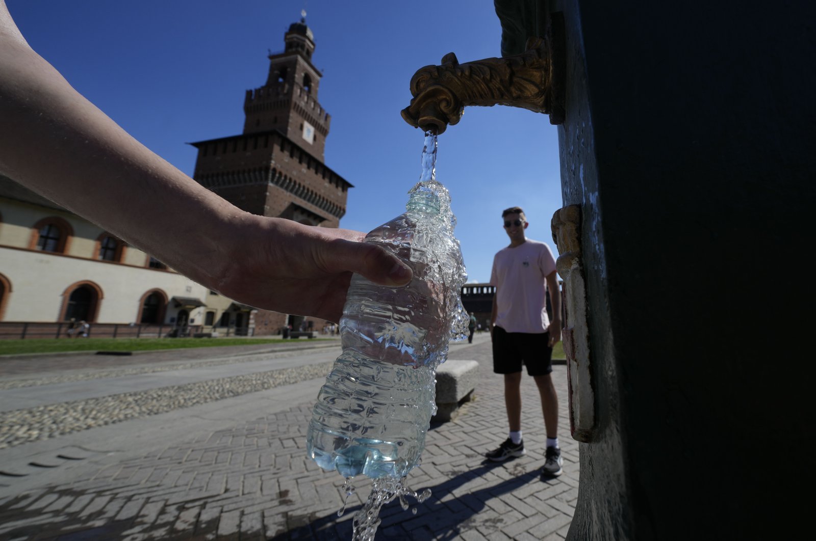 Tourists fill plastic bottles with water from a public fountain at Sforzesco Castle, in Milan, Italy, June 25, 2022. (AP Photo)