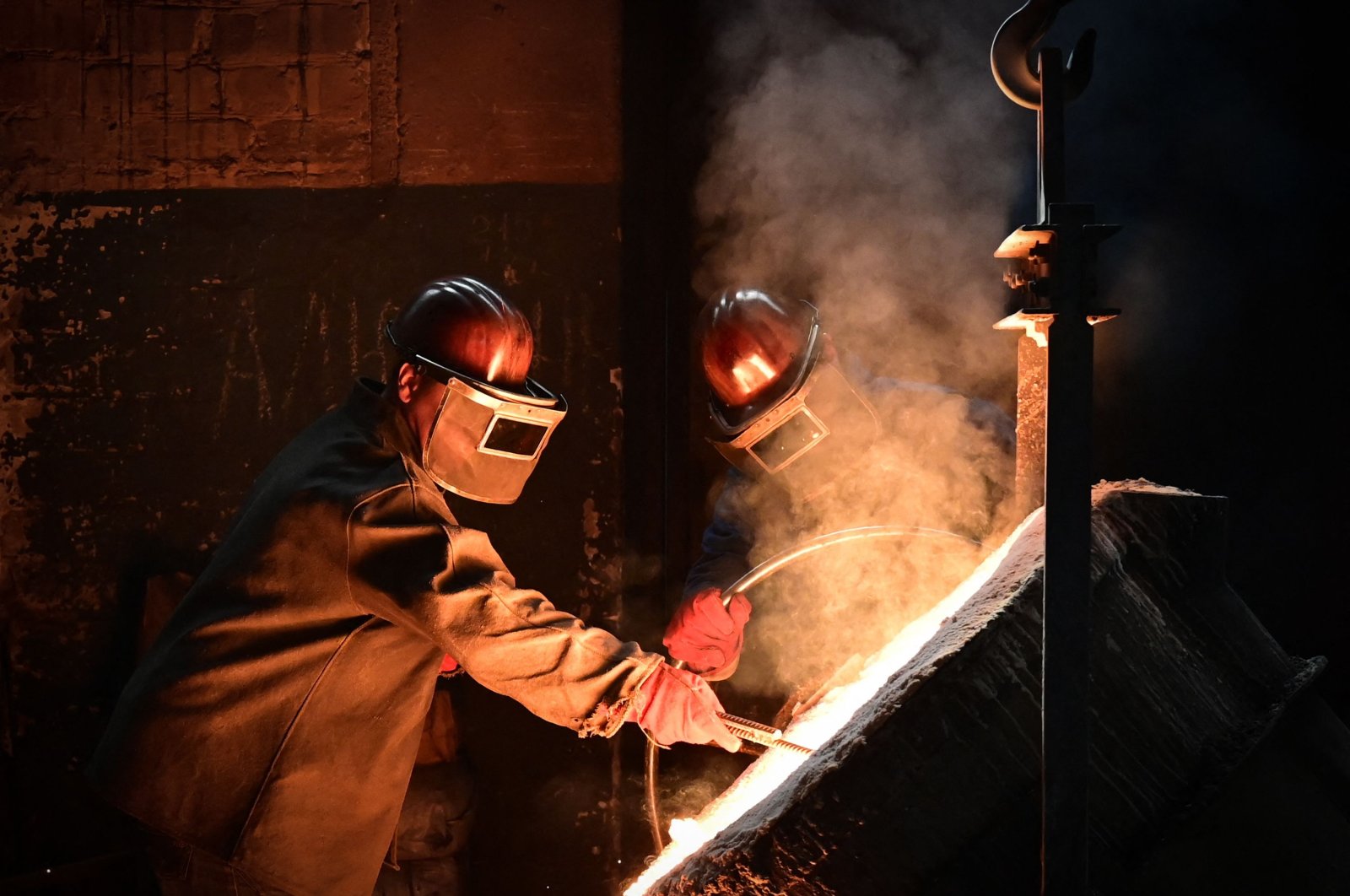 Workers pour metal at a private Berdyansk foundry in Berdyansk, amid the ongoing Russian military action in Ukraine, June 14, 2022. (AFP Photo) 