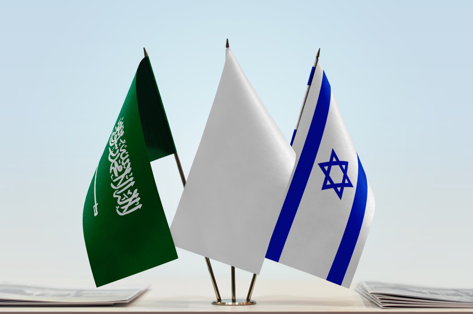 The flags of Saudi Arabia (L) and Israel (R) with a white flag in the middle. (Shutterstock Photo)