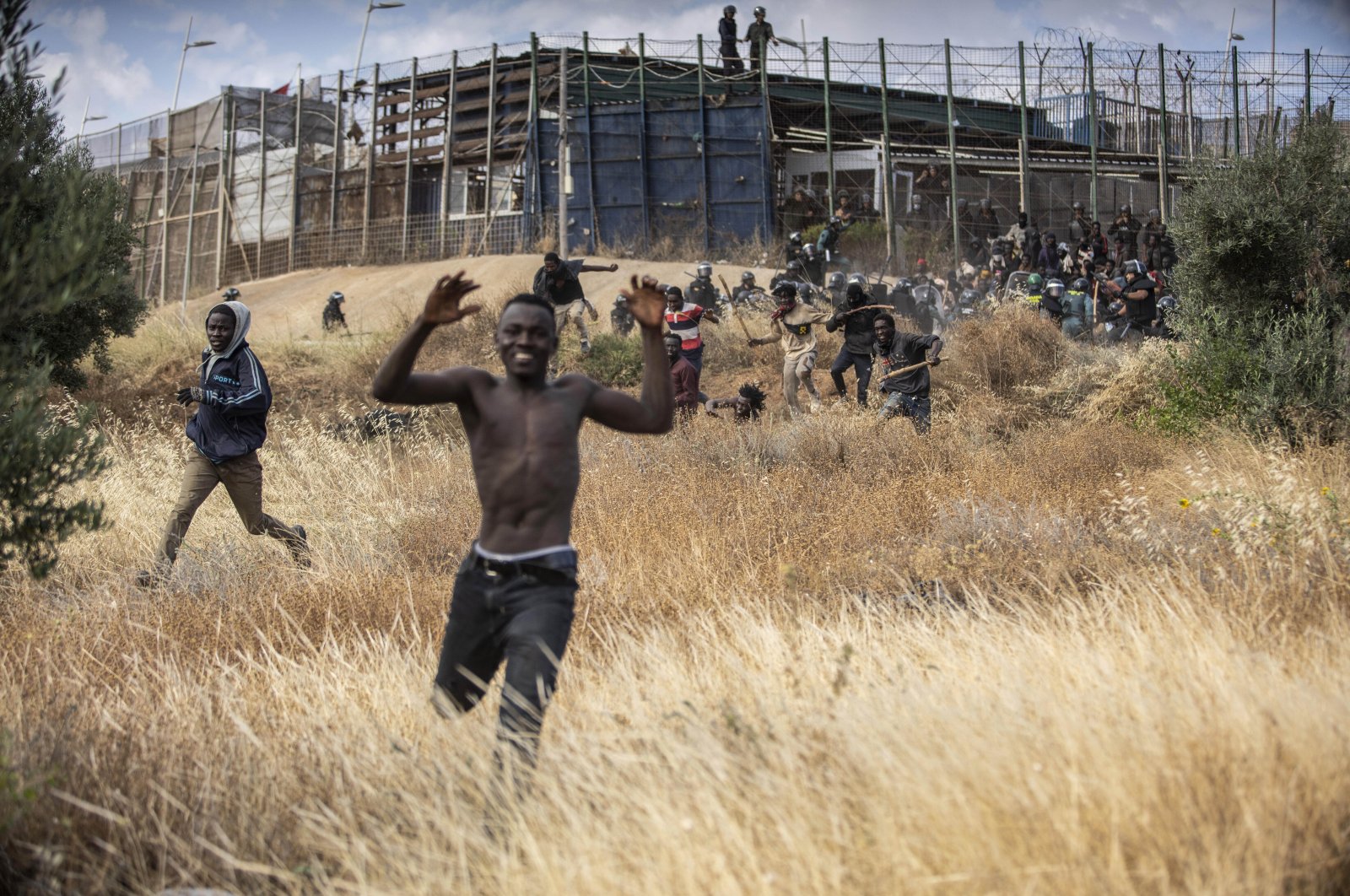 Migrants run on Spanish soil after crossing the fences separating the Spanish enclave of Melilla from Morocco in Melilla, Spain, Friday, June 24, 2022. (AP Photo)