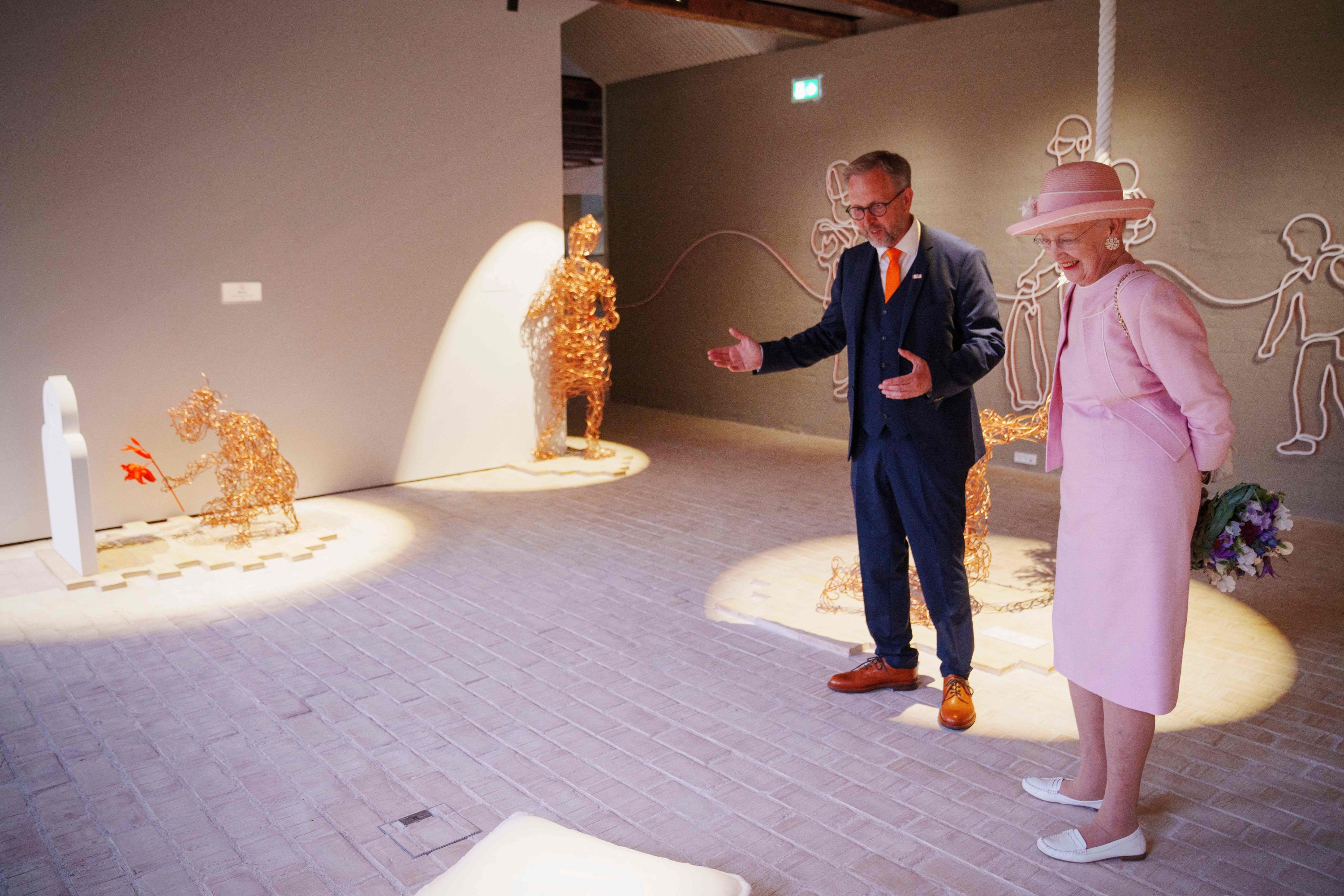 Ratu Denmark Margrethe (kanan) dan direktur museum Claus Kjeld Jensen mengunjungi pameran saat peresmian museum pengungsi Denmark yang baru FLUGT (escape) di Oksboel, Denmark, 25 Juni 2022. (AFP Photo)