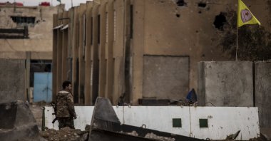 A YPG terrorist keeps watch by a prison that was attacked by Daesh, Hassakeh, Syria, Feb. 8, 2022. (AP Photo)