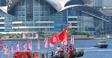 A fishing boat with banners and flags to mark the 25th anniversary of the handover of Hong Kong from Britain to China sails through Victoria harbor, Hong Kong, June 28, 2022. (AFP Photo)