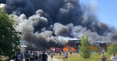 People watch as smoke bellows after a Russian missile strike hit a crowded shopping mall, in Kremenchuk, Ukraine, June 27, 2022. (AP Photo)