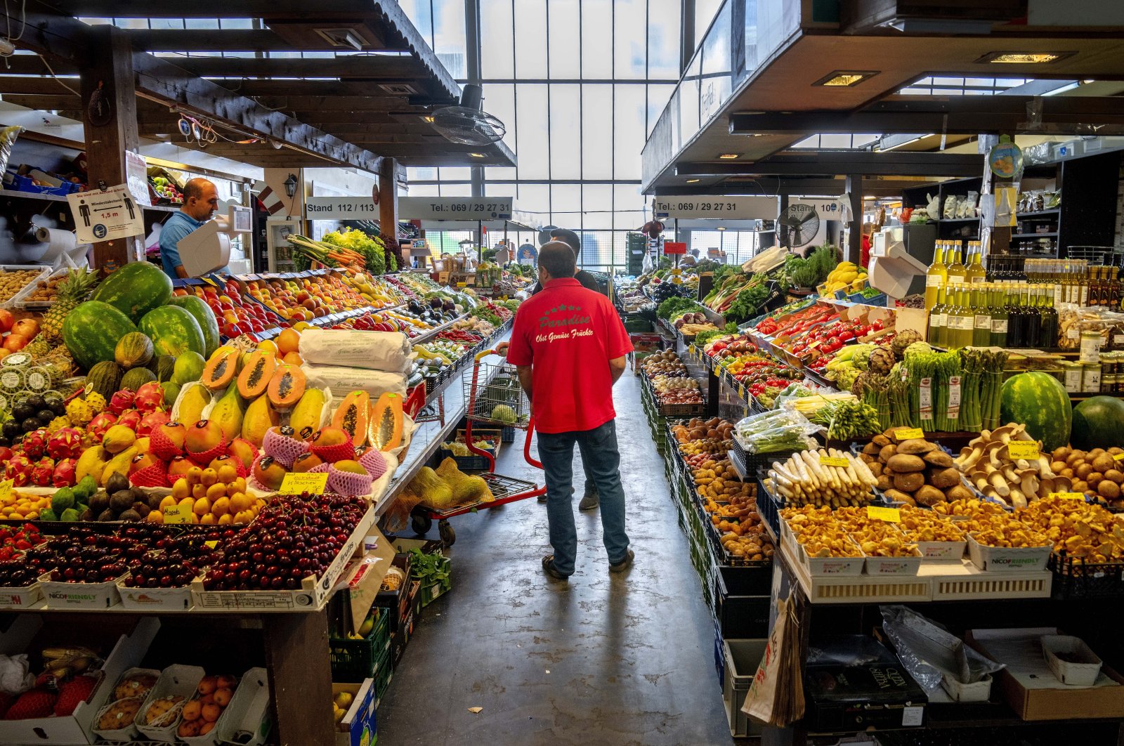 Fruit and vegetable sellers walk among the stands in the market hall in Frankfurt, Germany, June 14, 2022. (AP Photo)