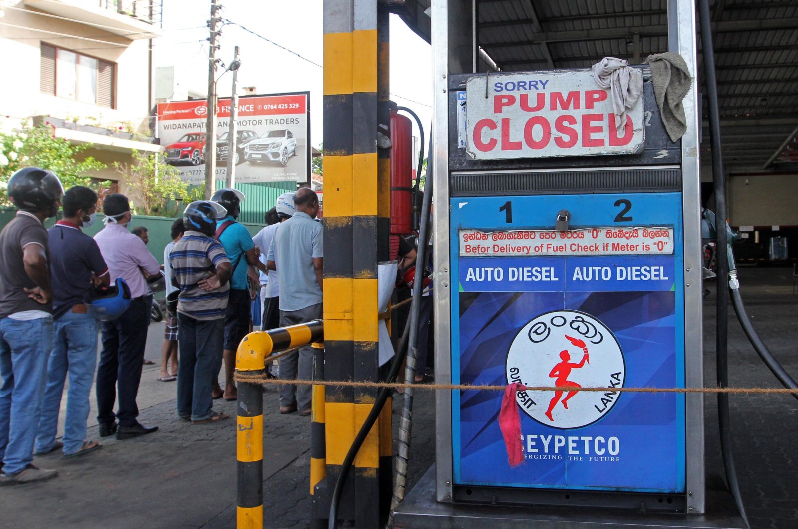 People stand outside a closed Ceylon Petroleum Corporation fuel station that ran out of gasoline in Colombo, Sri Lanka, June 27, 2022. (AFP Photo)