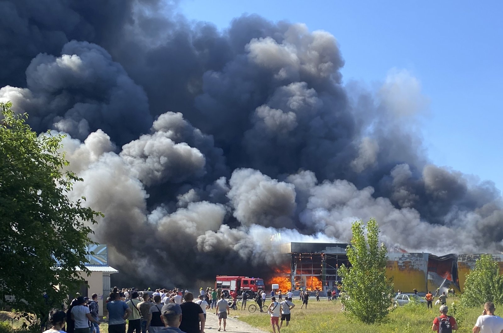 People watch as smoke bellows after a Russian missile strike hit a crowded shopping mall, in Kremenchuk, Ukraine, June 27, 2022. (AP Photo)
