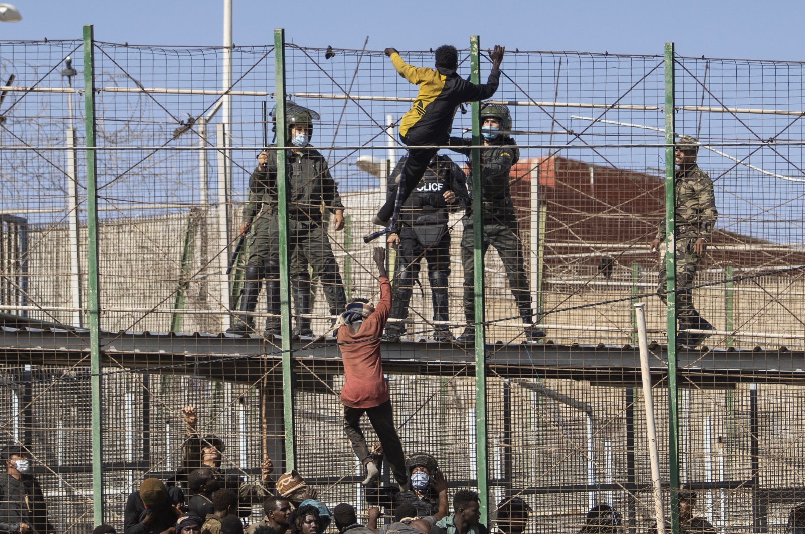 Migrants climb the fences separating the Spanish enclave of Melilla from Morocco in Melilla, Spain, June 24, 2022. (AP Photo)