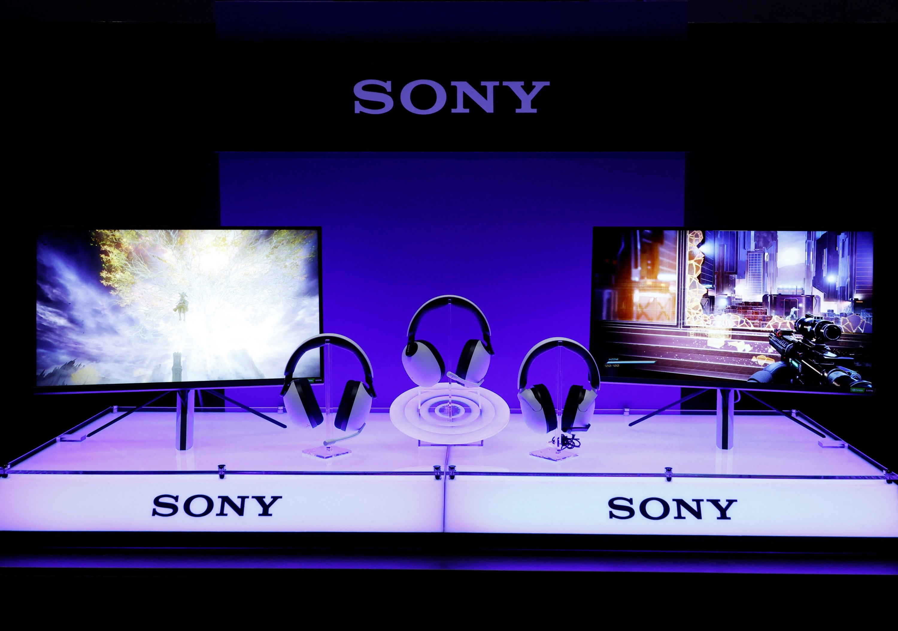 Visitors are reflected in a PlayStation 4 sign outside the Sony