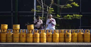 People have breakfast while sitting by a line of empty gas canisters that are placed outside the Galle International Cricket Stadium, in Galle, Sri Lanka, June 28, 2022. (AP Photo)