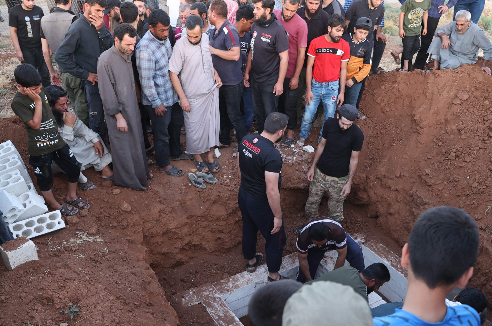 Mourners bury a member of the Syrian National Army during a group funeral held in Taftanaz, northwestern Idlib, Syria, June 29, 2022. (AFP Photo)