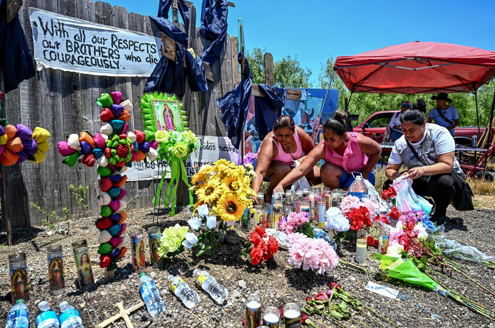 People place flowers and candles at a makeshift memorial where a tractor-trailer was discovered with migrants inside, outside San Antonio, Texas, U.S., June 29, 2022. (AFP Photo)