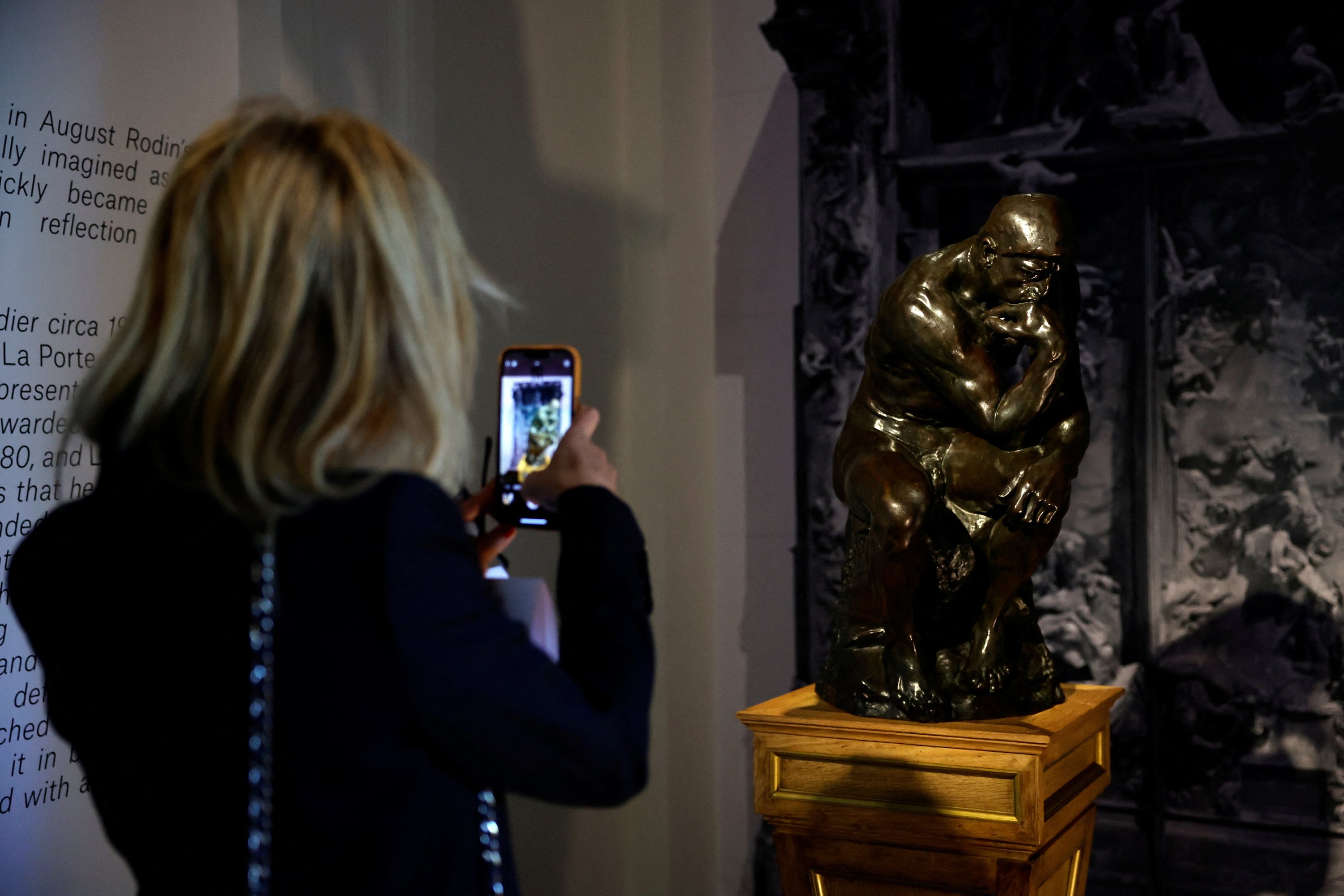 A woman takes a picture of a posthumous cast of 'The Thinker' (around 1928) by French sculptor Auguste Rodin (1840-1917) on display before its auction at Christie's auction house in Paris, France, June 27, 2022. (REUTERS)