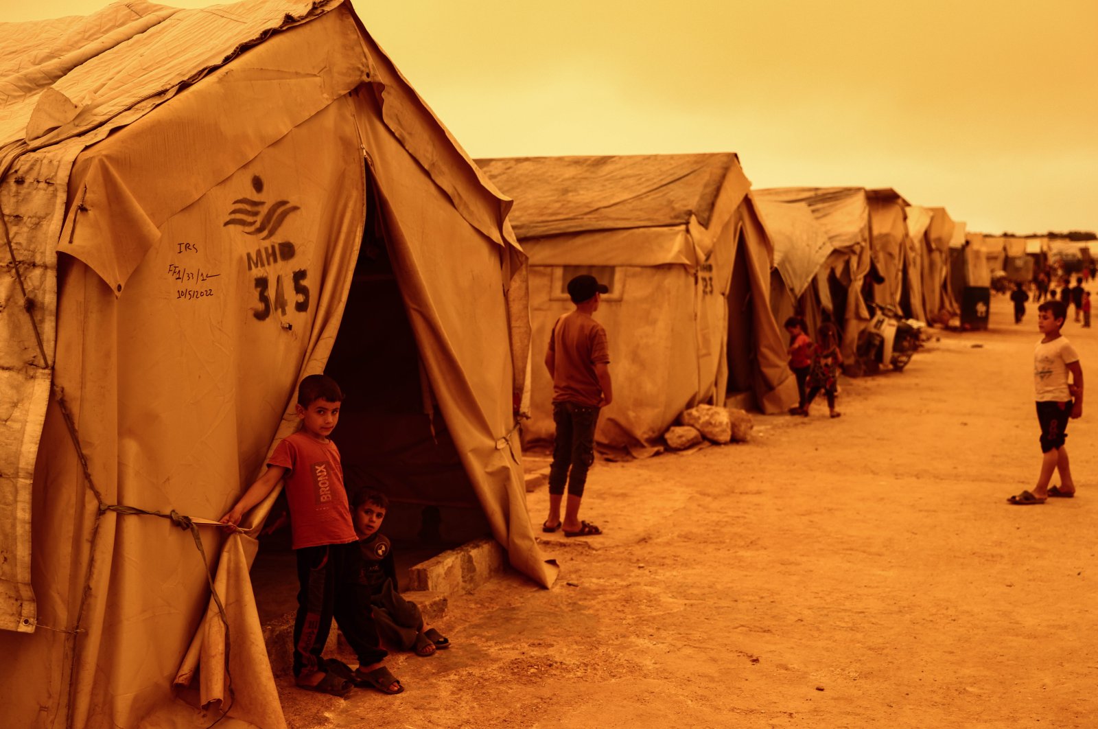 Children stand outside their tents at a camp for displaced people during a sandstorm hitting Idlib, northern Syria, June 2, 2022. (Reuters Photo)
