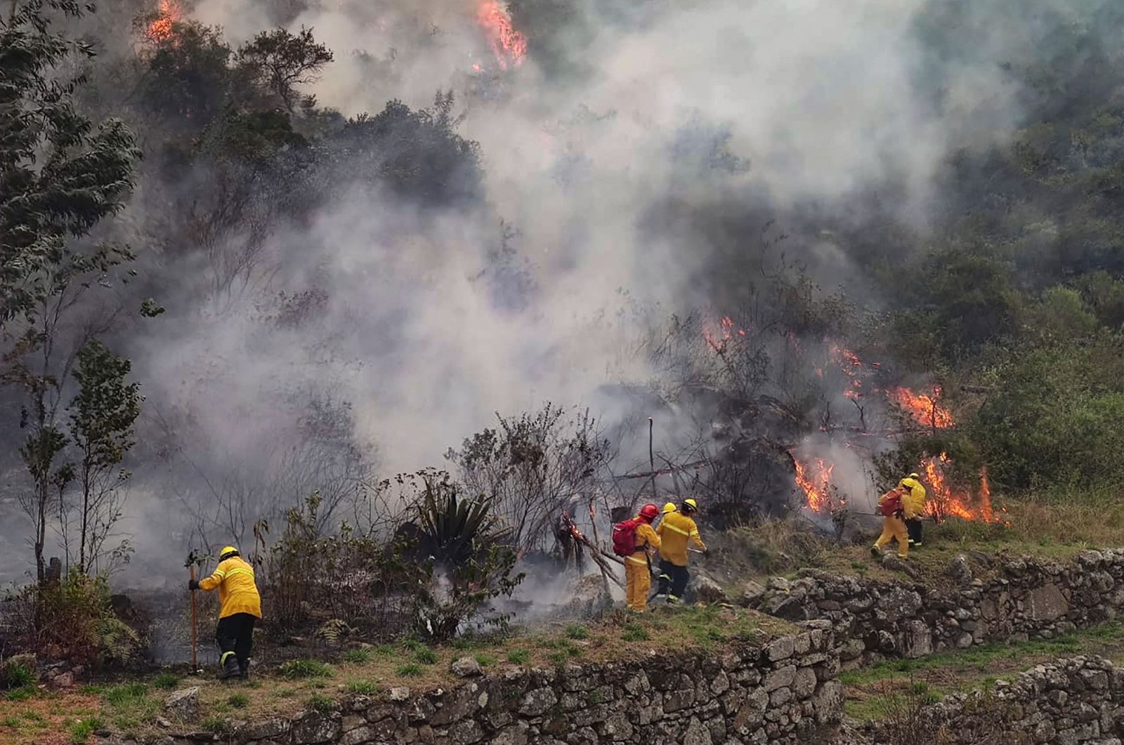 Firefighters are working to put out a fire in the bush surrounding the ruins of Llamakancha, a sector in the archaeological site of Machu Picchu, Peru, June 28, 2022. (Machu Picchu Municipality via AFP)