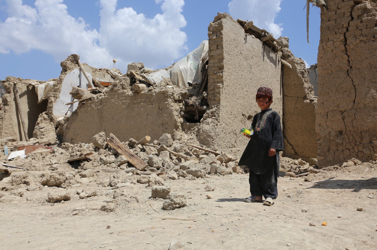 A child stands next to a collapsed building in Paktika, Afghanistan, June 29, 2022. (AA PHOTO)