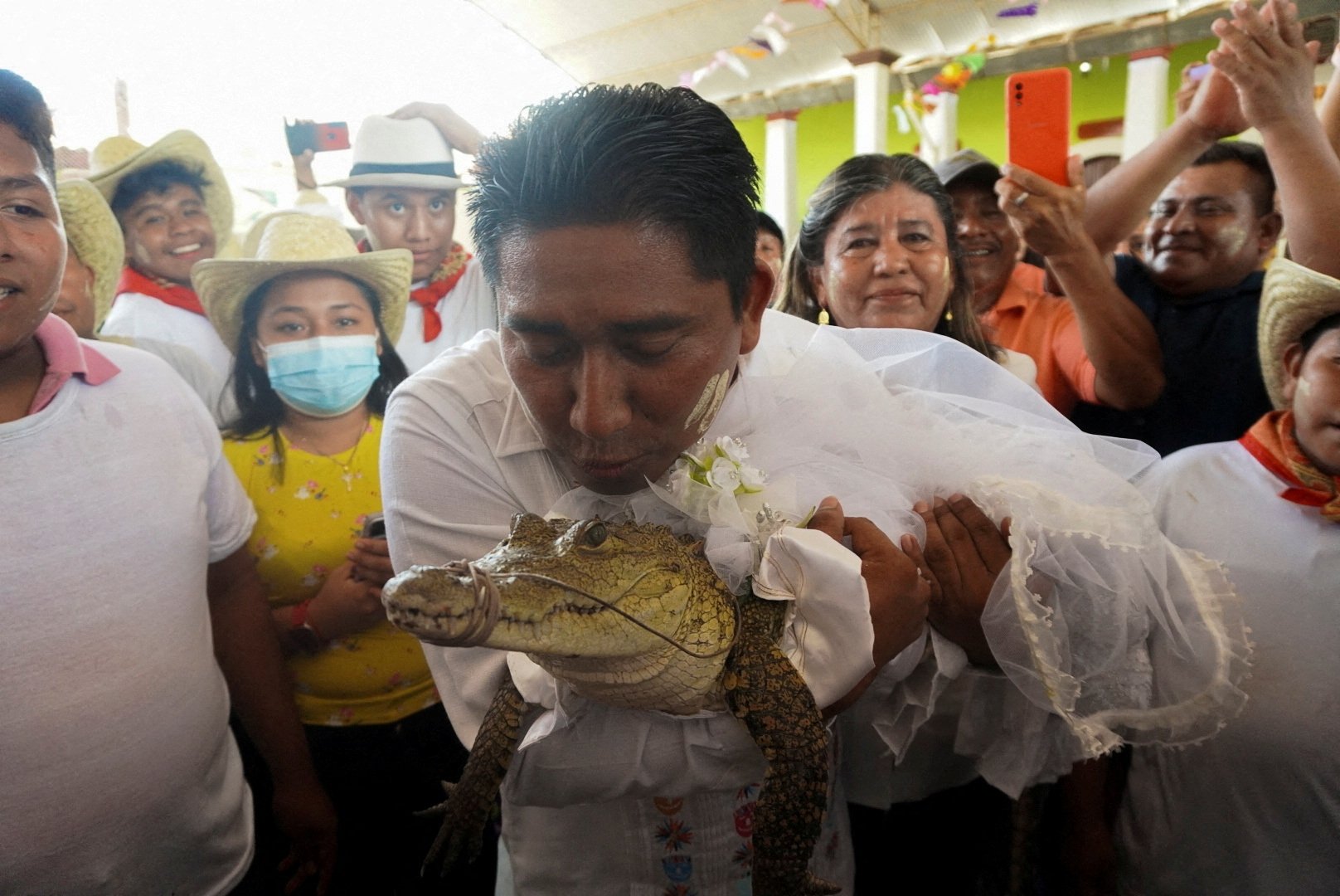 The San Pedro Huamelula Mayor Victor Hugo Sosa kisses an alligator dressed as a bride during a traditional ritual marriage between the mayor and the reptile that depicts a princess, as a prayer to plead for nature's bounty, San Pedro Huamelula, Oaxaca state, Mexico, June 30, 2022. (Reuters Photo)