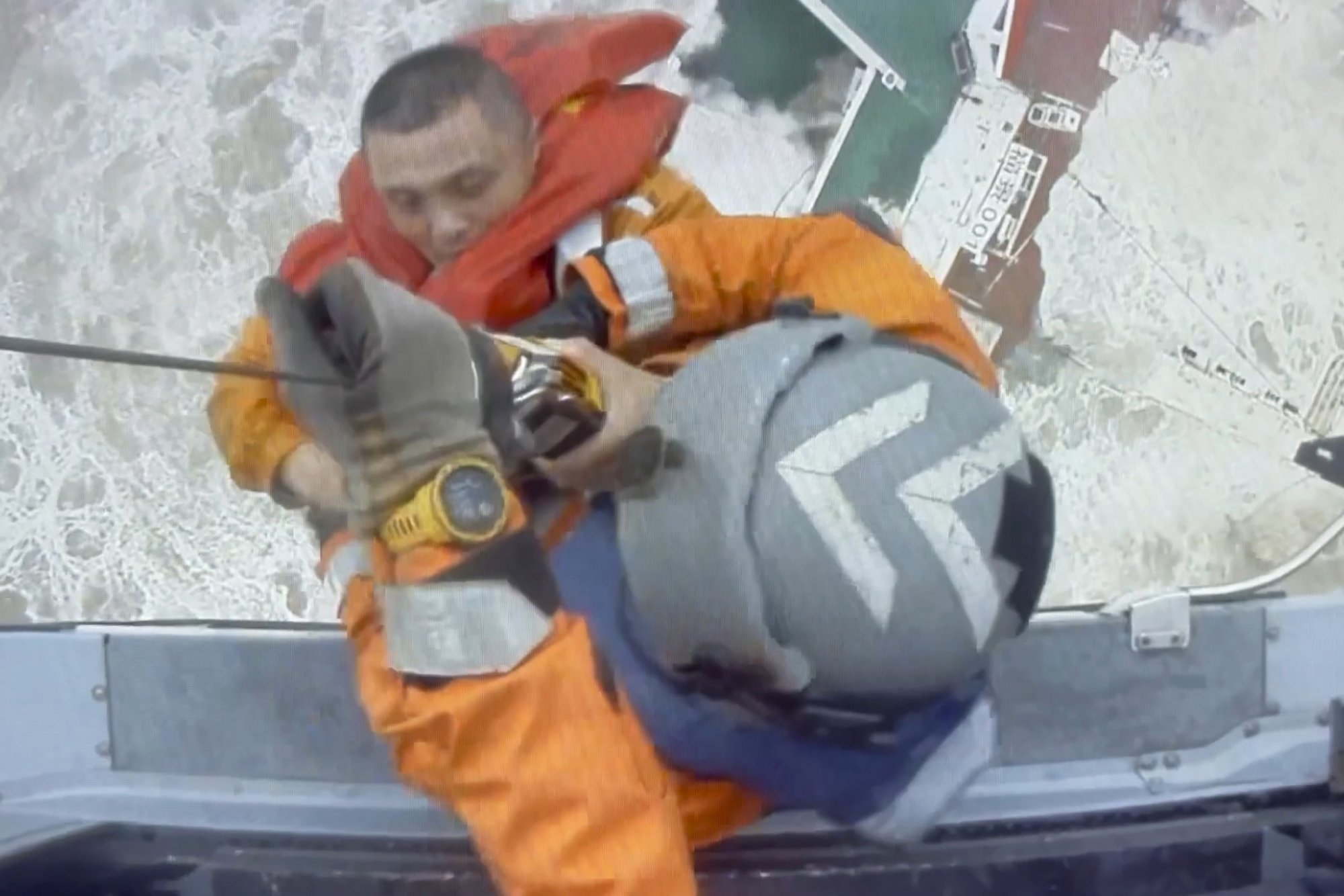 In this image released by Hong Kong Government Flying Service, helicopter crew members winch up a man from a sinking ship in the South China Sea, 300 kilometers (186 miles) south of Hong Kong, July 2, 2022, as Typhoon Chaba was moving in the area. The industrial support ship operating in the South China Sea has sunk with the possible loss of more than two dozen crew members, rescue services in Hong Kong said Saturday. (Hong Kong Government Flying Service via AP)