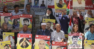 Protesters, including an Orthodox Christian priest (back C) and Muslim imam (front C), lift placards during a demonstration in front of the Red Cross in support of Palestinians detained in Israeli prisons, Ramallah city, occupied West Bank, Palestine, June 14, 2022. (AFP Photo)