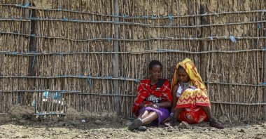 Tanzanian Maasai women sit next to a manyatta house under construction to accomodate them at a remote village bordering Kenya and Tanzania in Narok, Kenya, June 23, 2022. (EPA Photo)