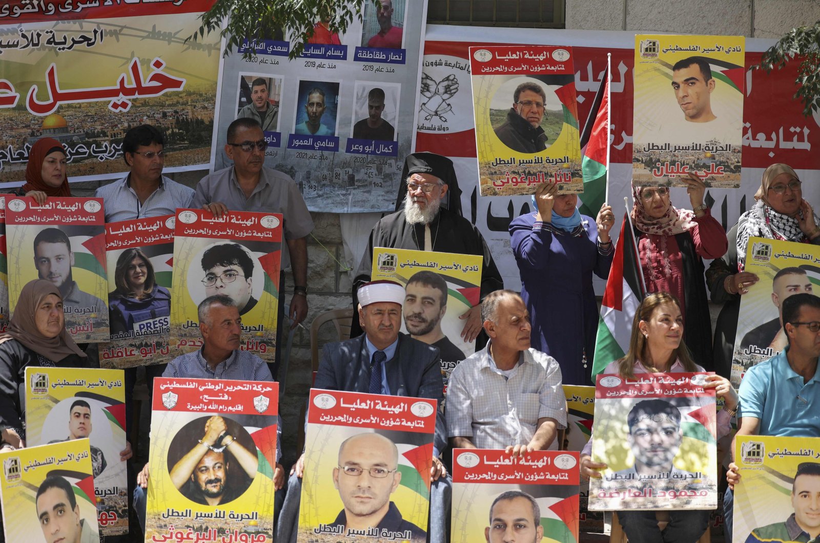 Protesters, including an Orthodox Christian priest (back C) and Muslim imam (front C), lift placards during a demonstration in front of the Red Cross in support of Palestinians detained in Israeli prisons, Ramallah city, occupied West Bank, Palestine, June 14, 2022. (AFP Photo)