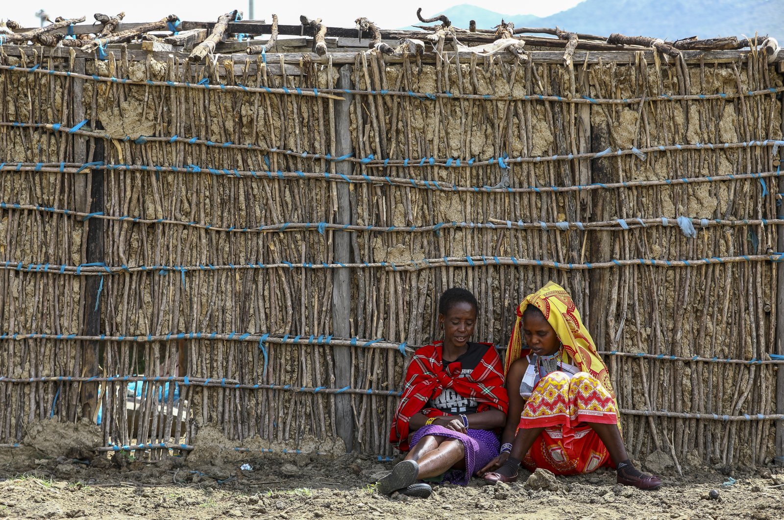 Tanzanian Maasai women sit next to a manyatta house under construction to accomodate them at a remote village bordering Kenya and Tanzania in Narok, Kenya, June 23, 2022. (EPA Photo)