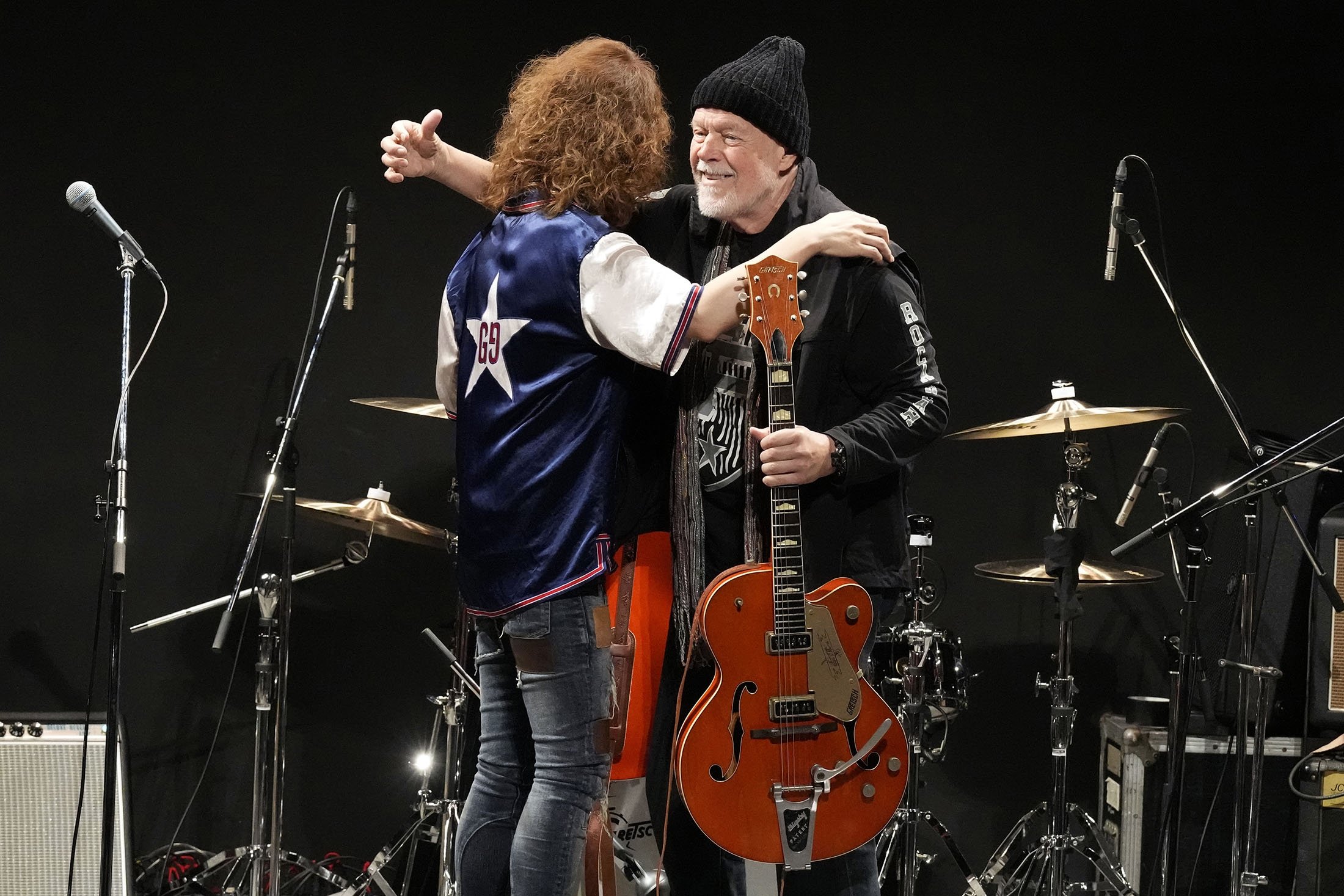 Canadian rock legend Randy Bachman, right, and Japanese musician TAKESHI embrace each other after Bachman reunites with his stolen Gretsch guitar during the Lost and Found Guitar Exchange Ceremony, at Canadian Embassy in Tokyo, Japan, July 1, 2022. (AP Photo)